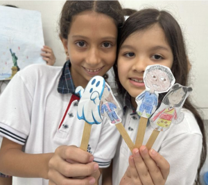 Students holding up popsicle stick puppets.