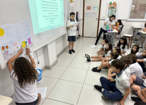 Students reading stories in front of a class.