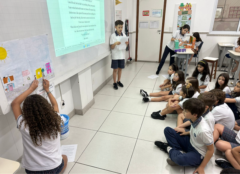 Students reading stories in front of a class.
